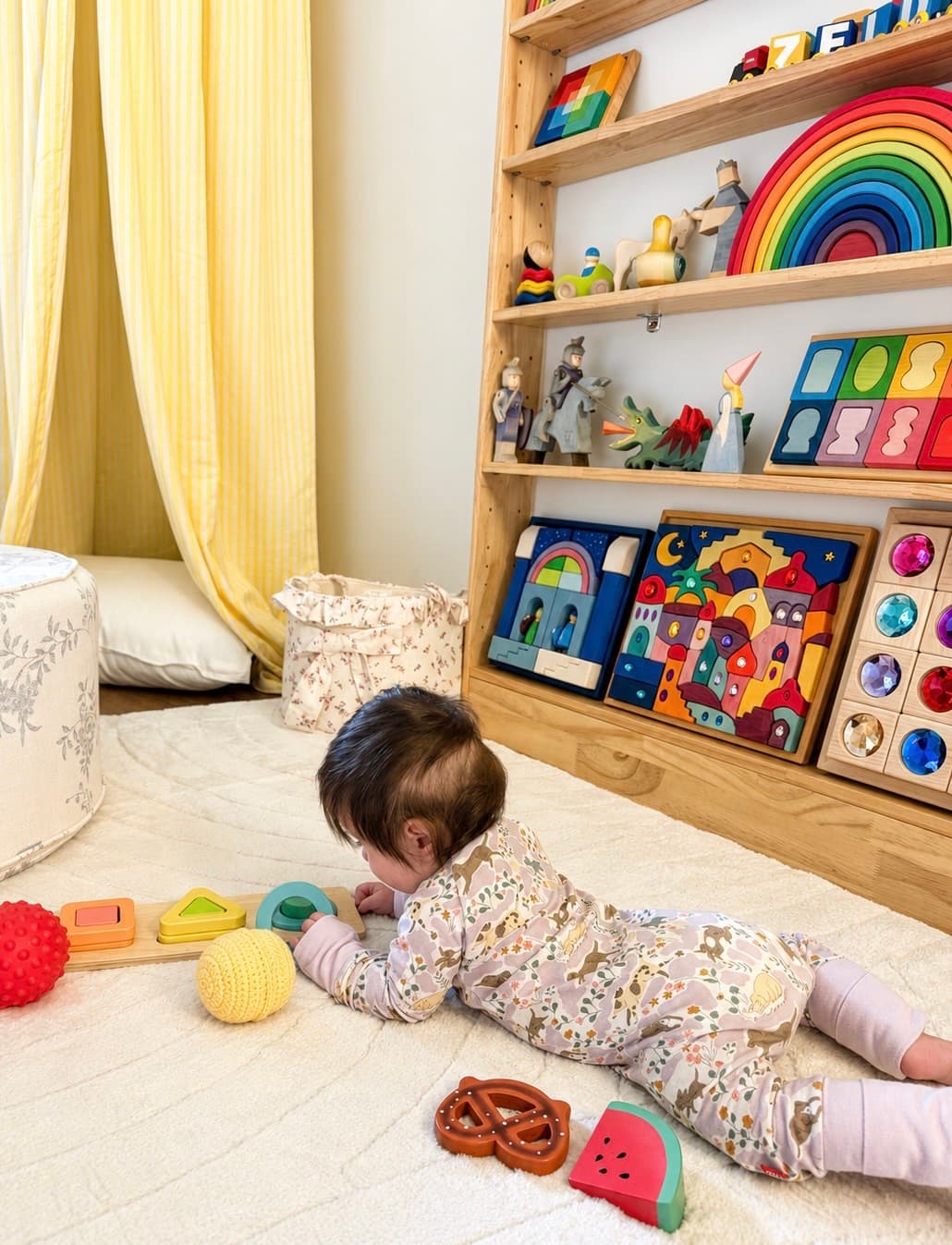 A baby reaching for wooden toys on a curated playroom shelf